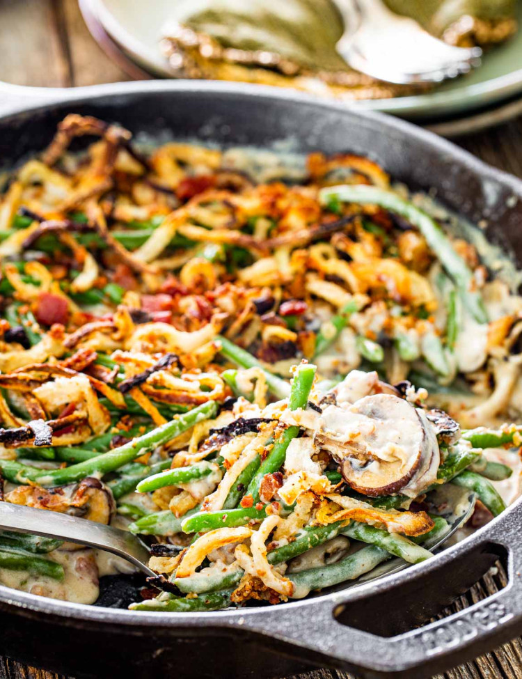 green bean casserole in a skillet with a serving spoon.