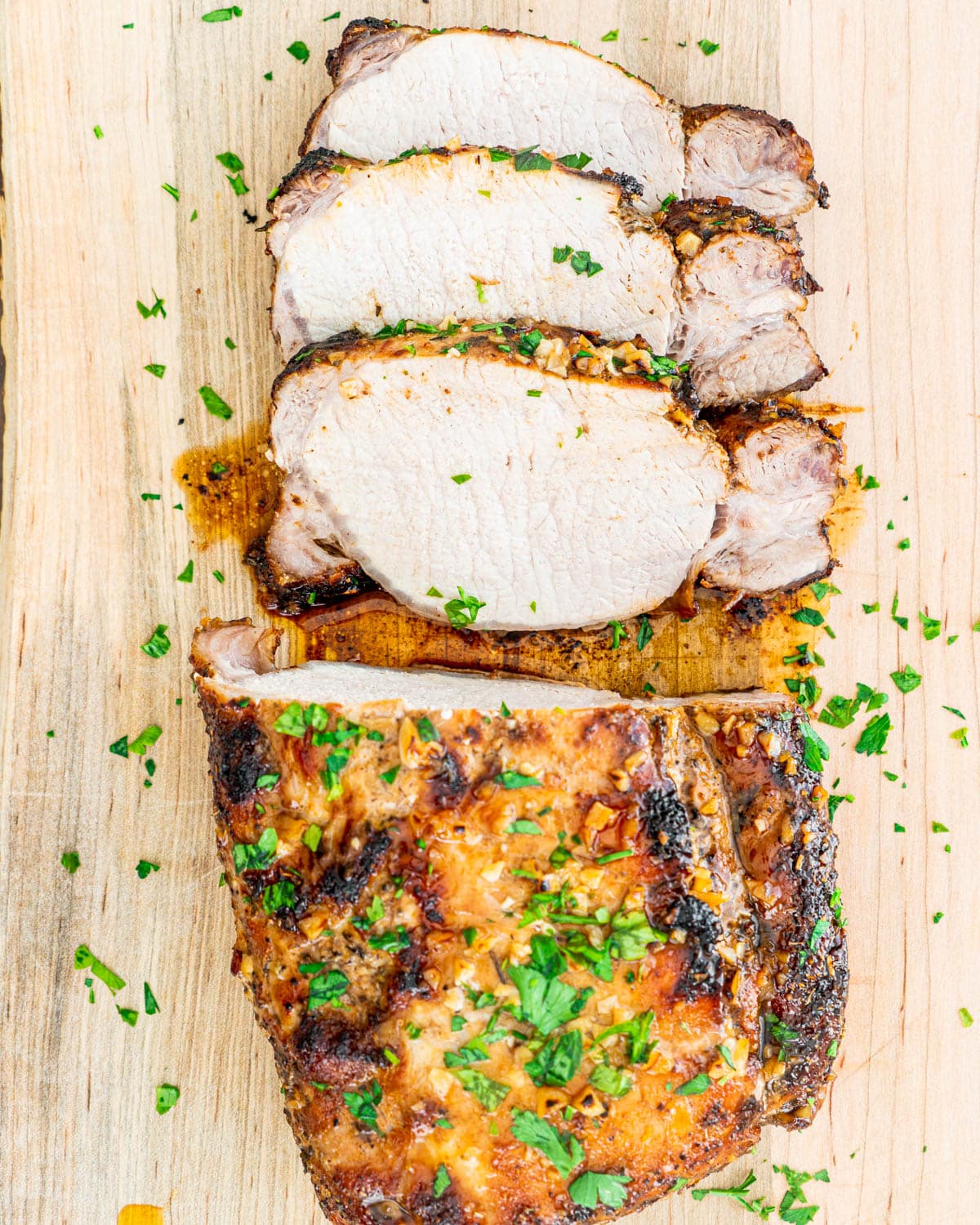 overhead shot of a pork loin on a cutting board sliced