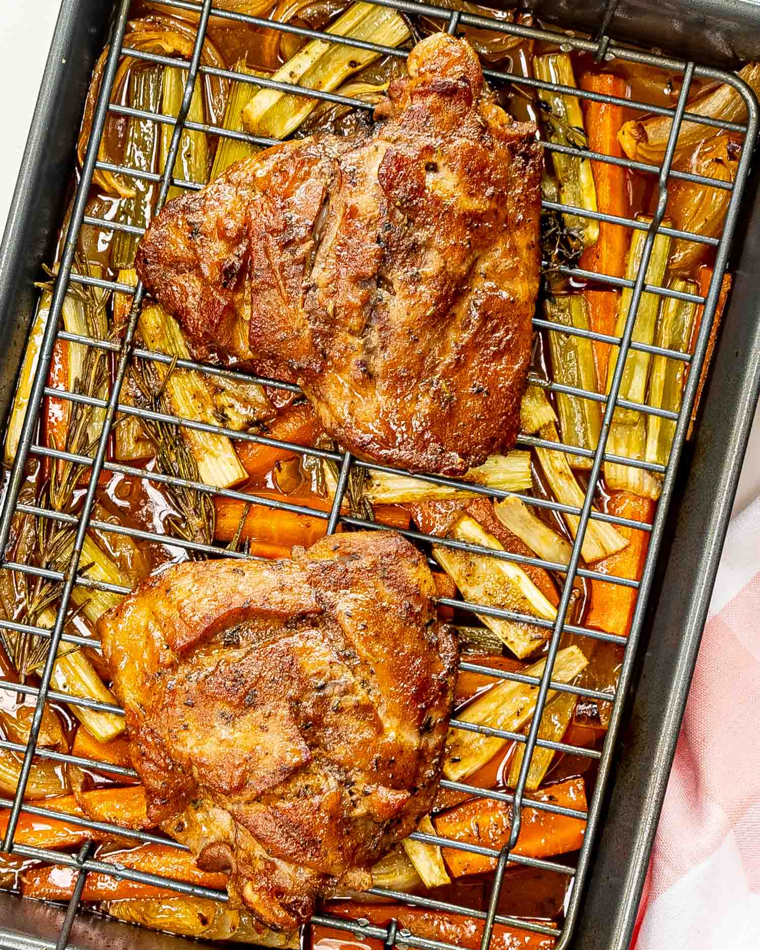 maple mustard roasted turkey thighs on a roasting pan along some roasted carrots and celery.