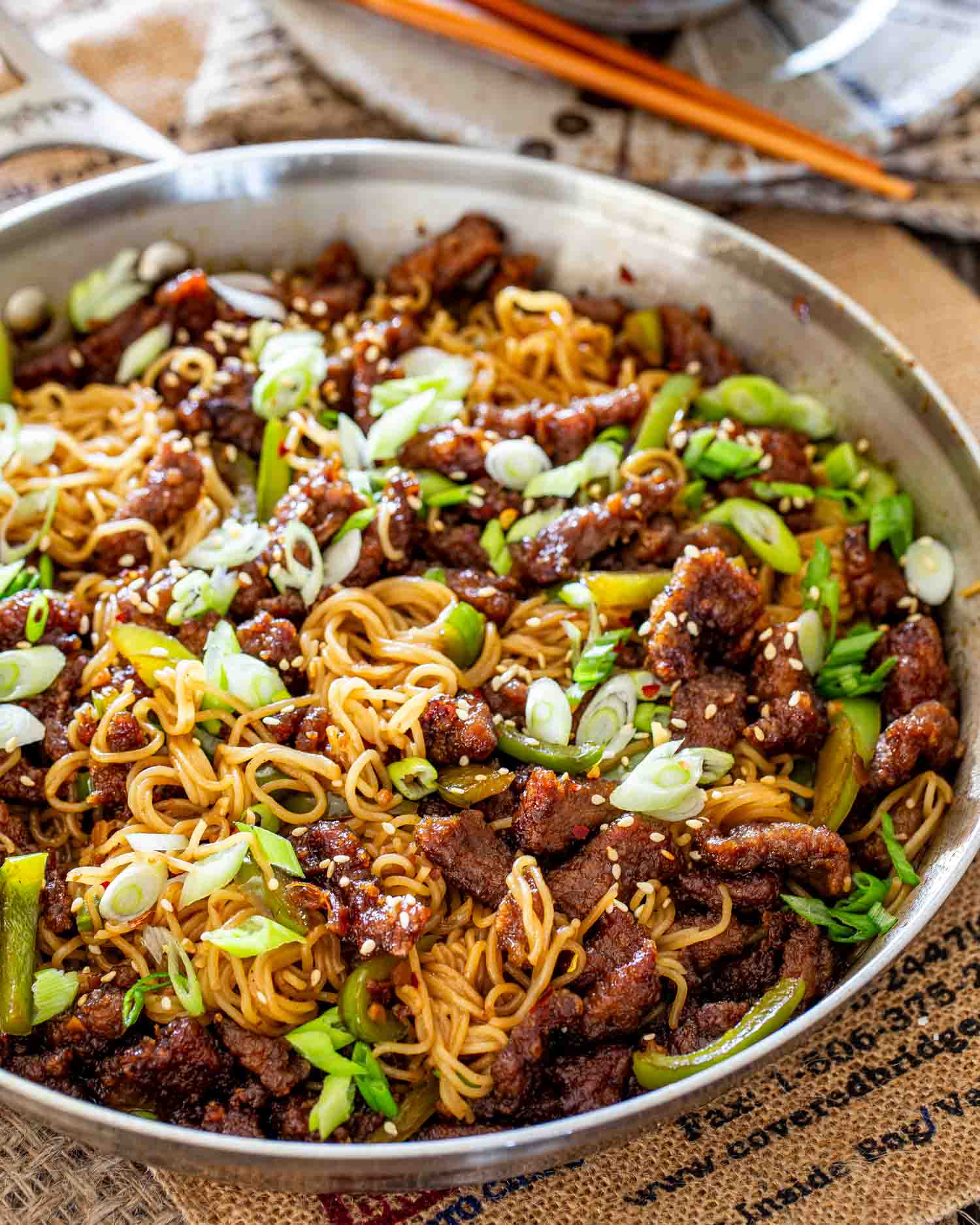 freshly made mongolian beef noodles in a skillet garnished with green onions.