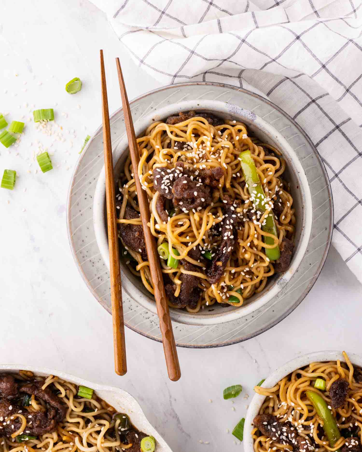 a serving of mongolian beef noodles with chopsticks in a bowl.