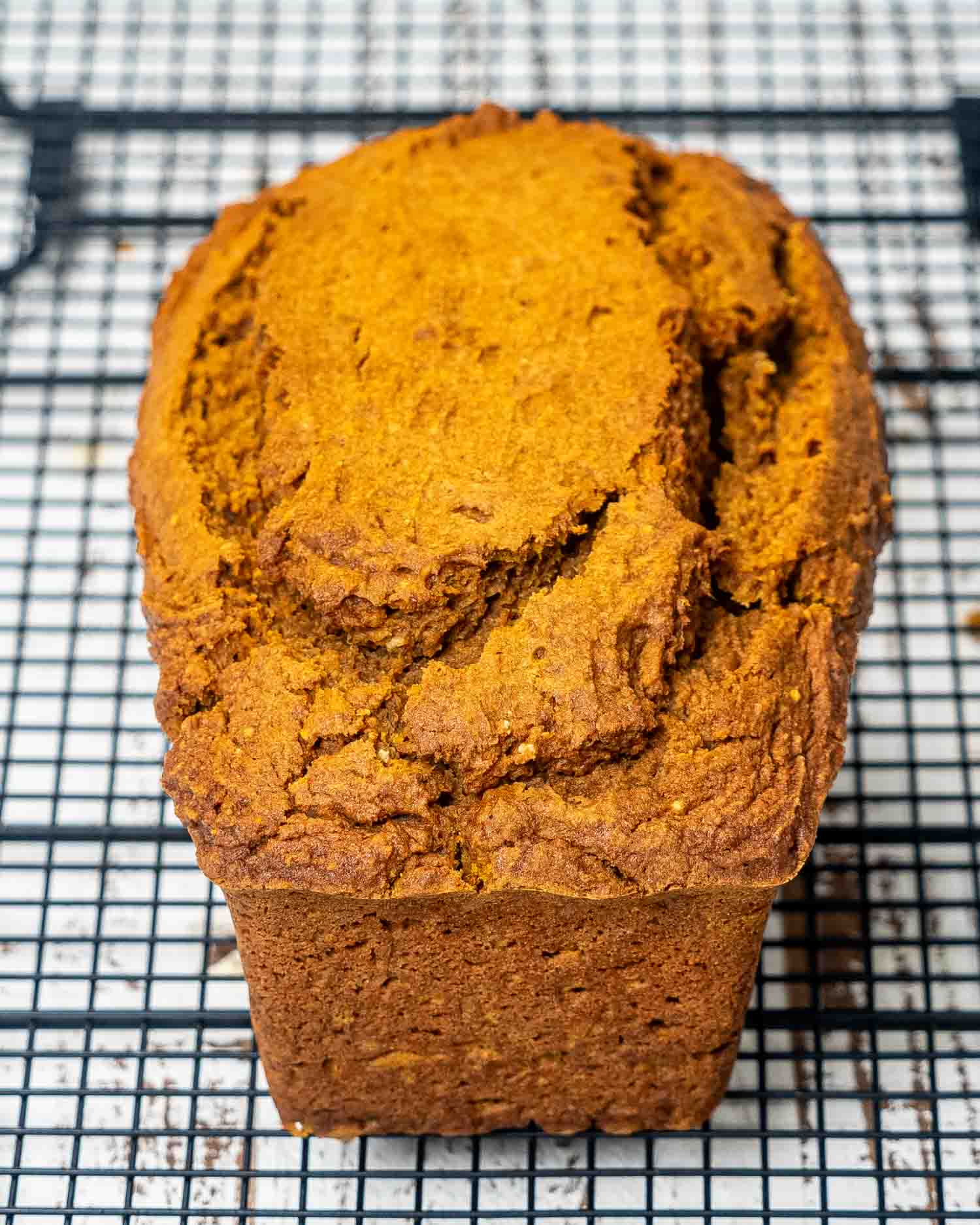 a freshly baked loaf of pumpkin bread cooling off on a cooling rack.