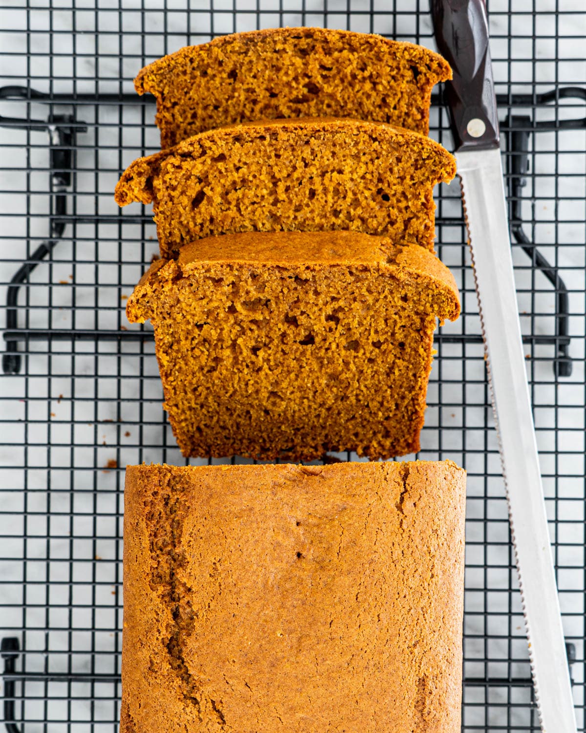overhead shot of a pumpkin bread with 3 slices on a cooling rack