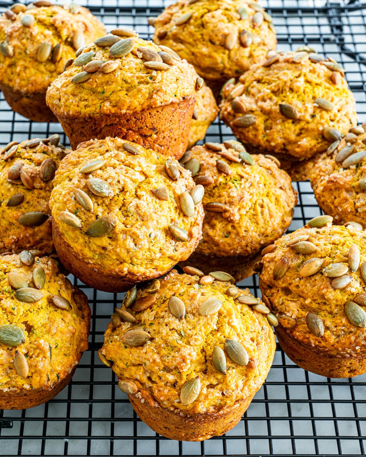 a bunch of Pumpkin Zucchini Muffins on top of each other on a cooling rack