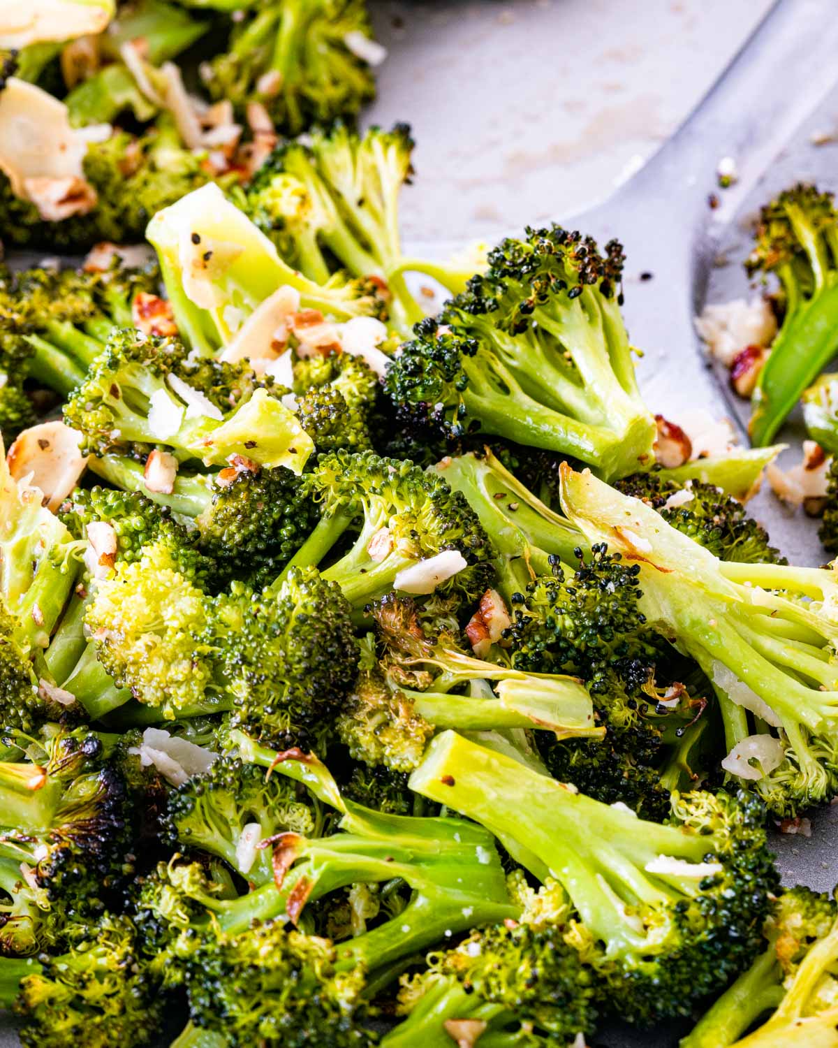 roasted broccoli on a baking sheet with a spatula.