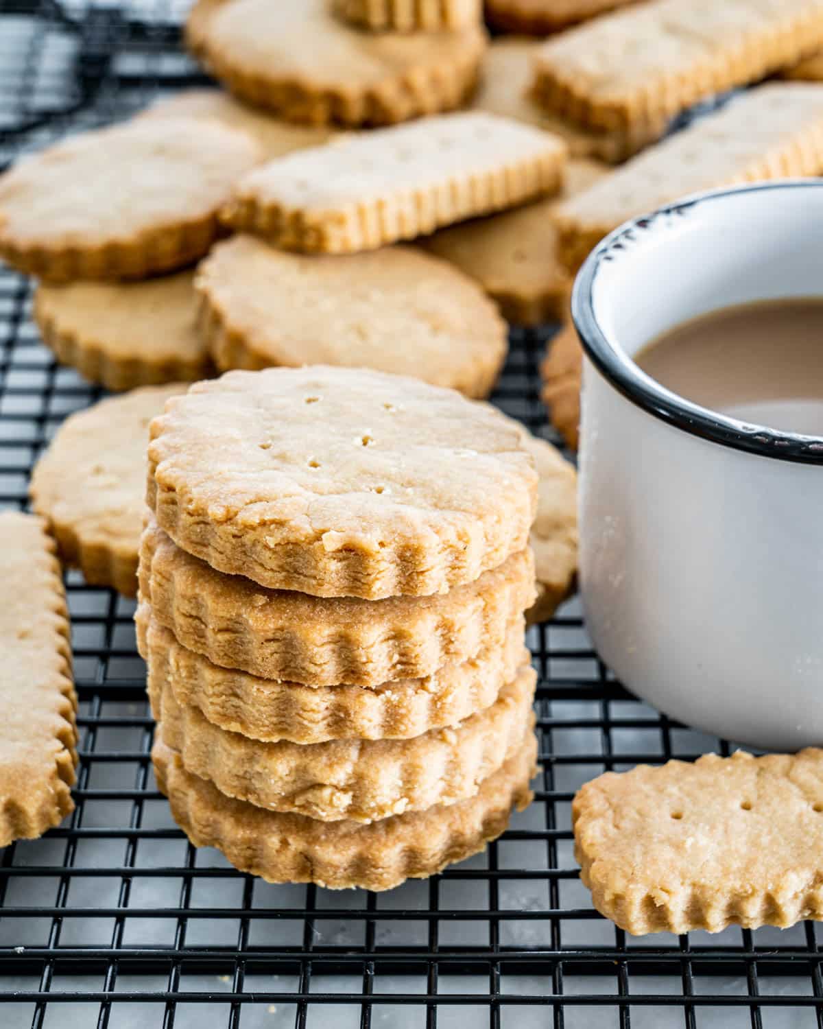 a bunch of scottish shortbread on a cooling rack next to a cup of coffee