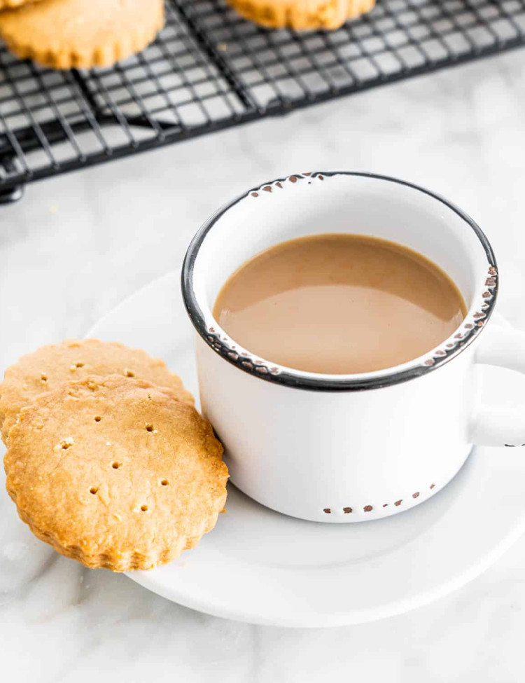 two scottish shortbread cookies on a plate with a cup of coffee