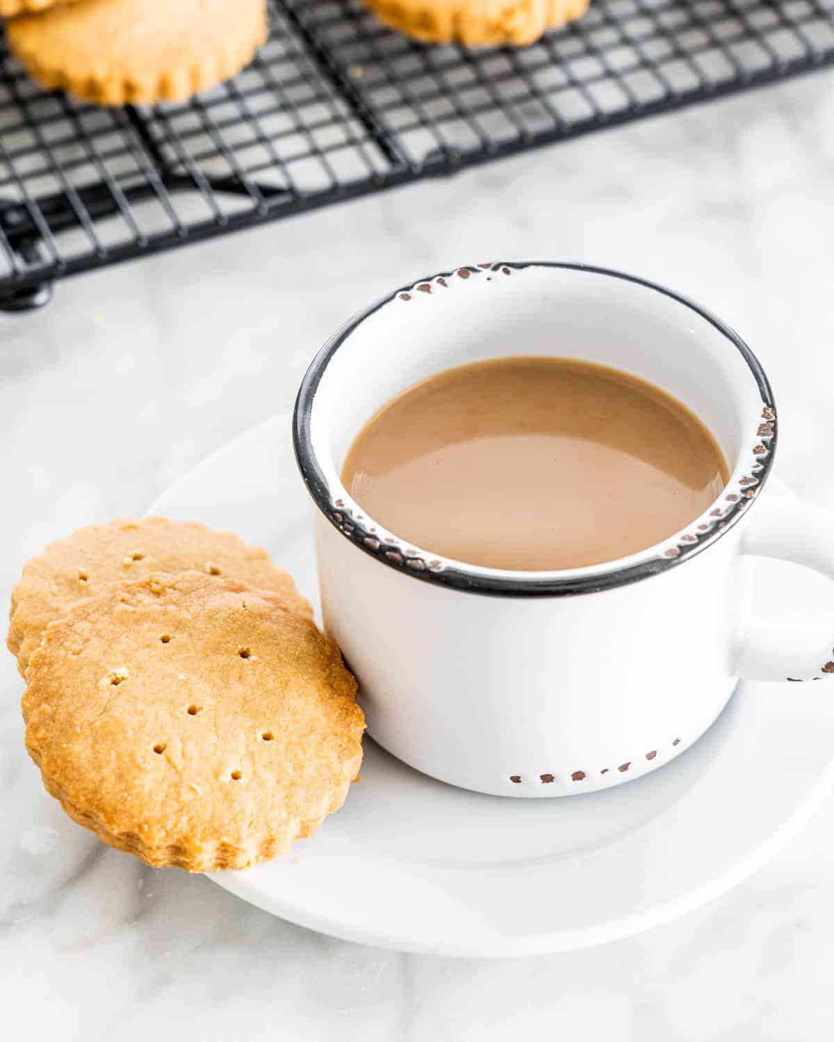 a cup of coffee with a couple scottish shortbread next to it