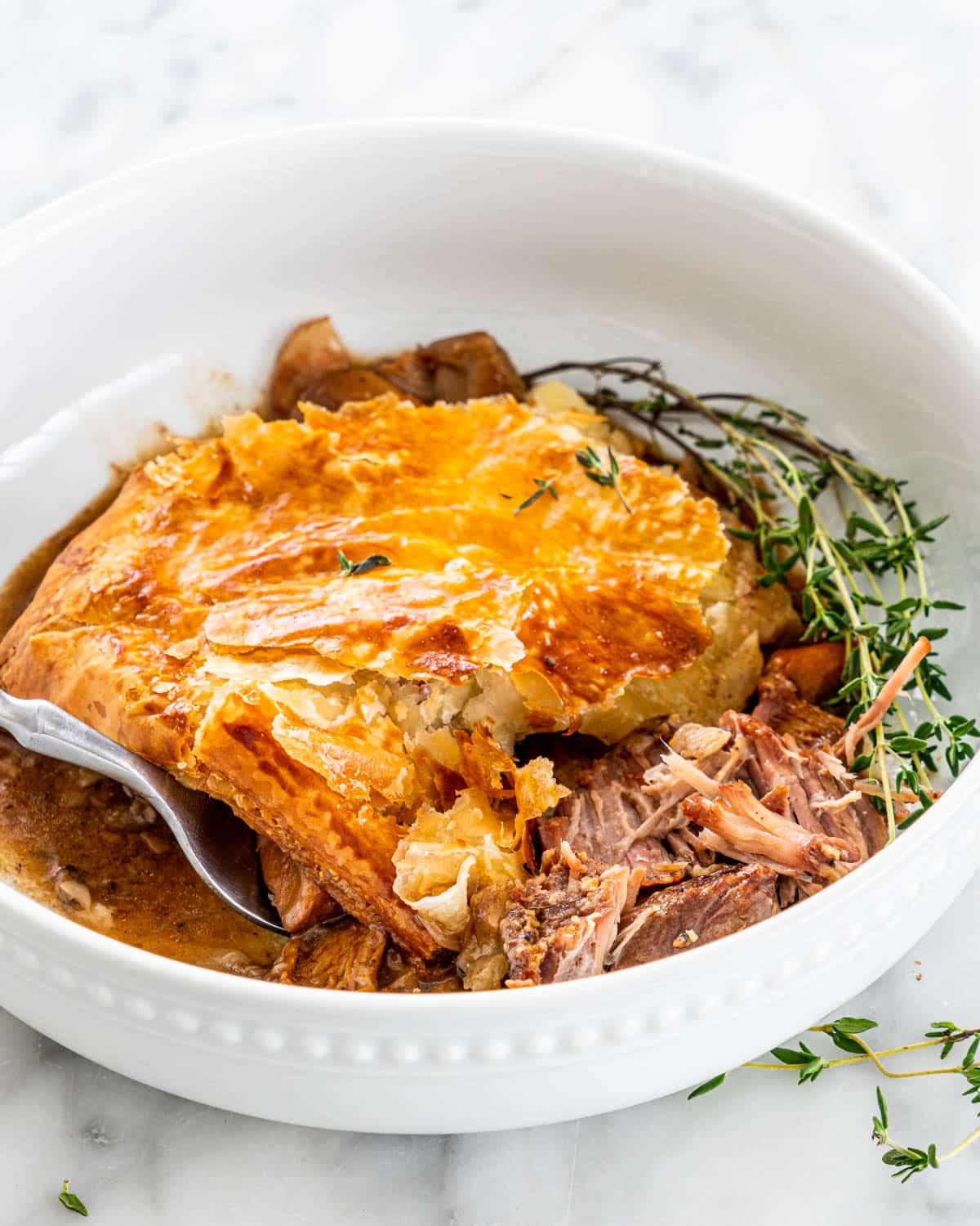 Steak and Mushroom Pie in a white bowl garnished with thyme