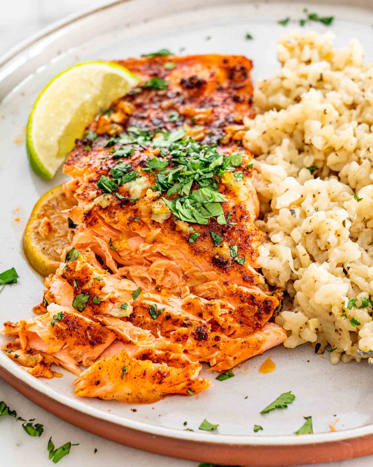 a serving of cilantro lime salmon along some rice on a white plate.