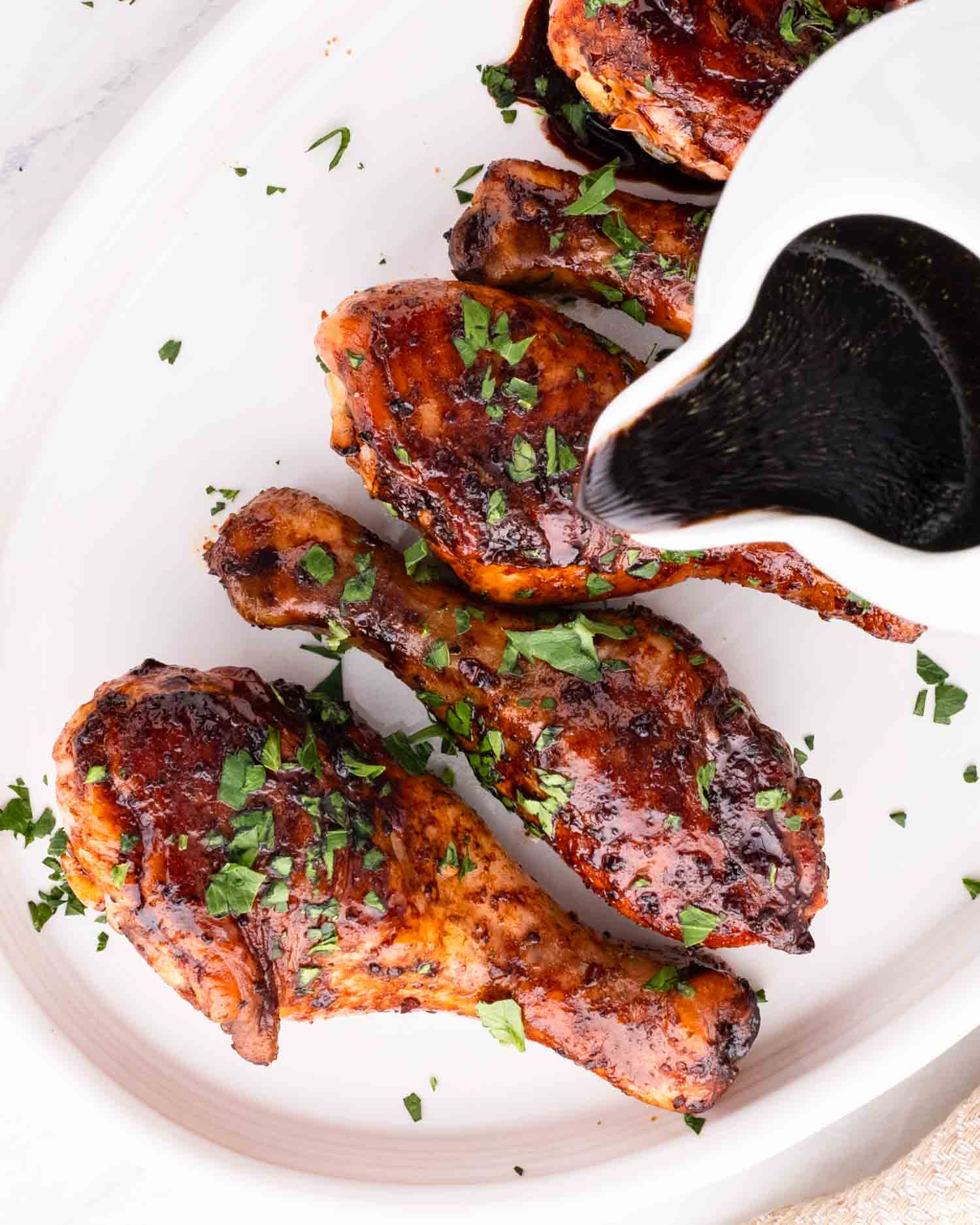 a white platter with freshly baked honey mustard chicken drumsticks garnished with parsley.