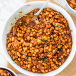 overhead shot of a bowl full of baked beans with a serving spoon in it