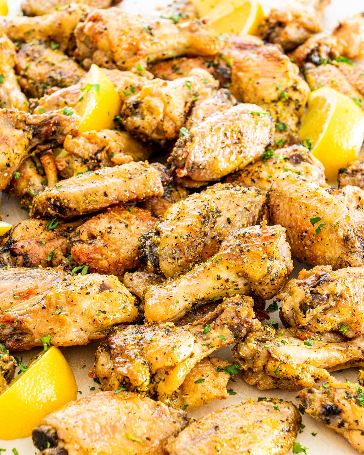 a bunch of lemon pepper wings garnished with lemon wedges and parsley