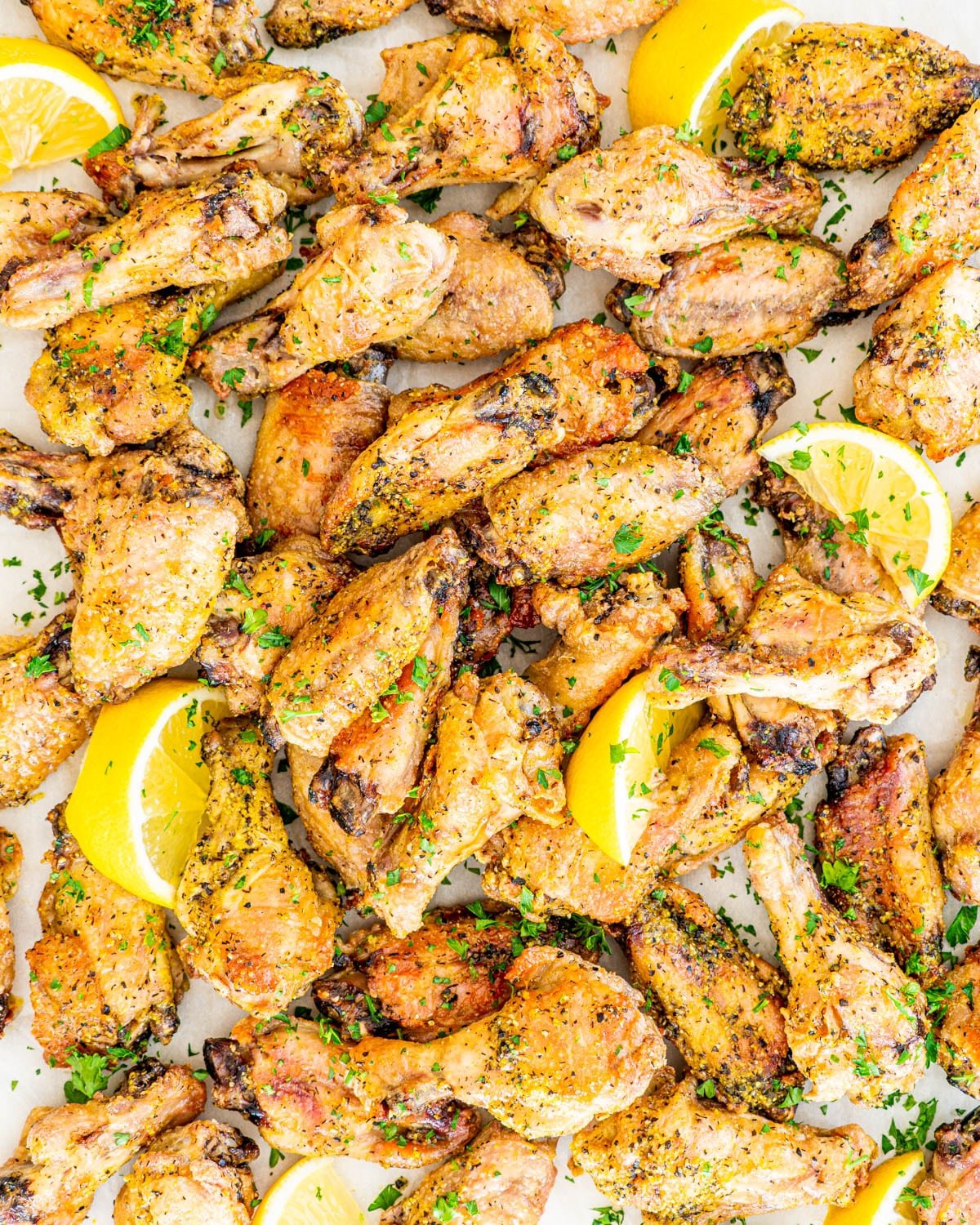 overhead shot of lemon pepper wings garnished with parsley and lemon wedges