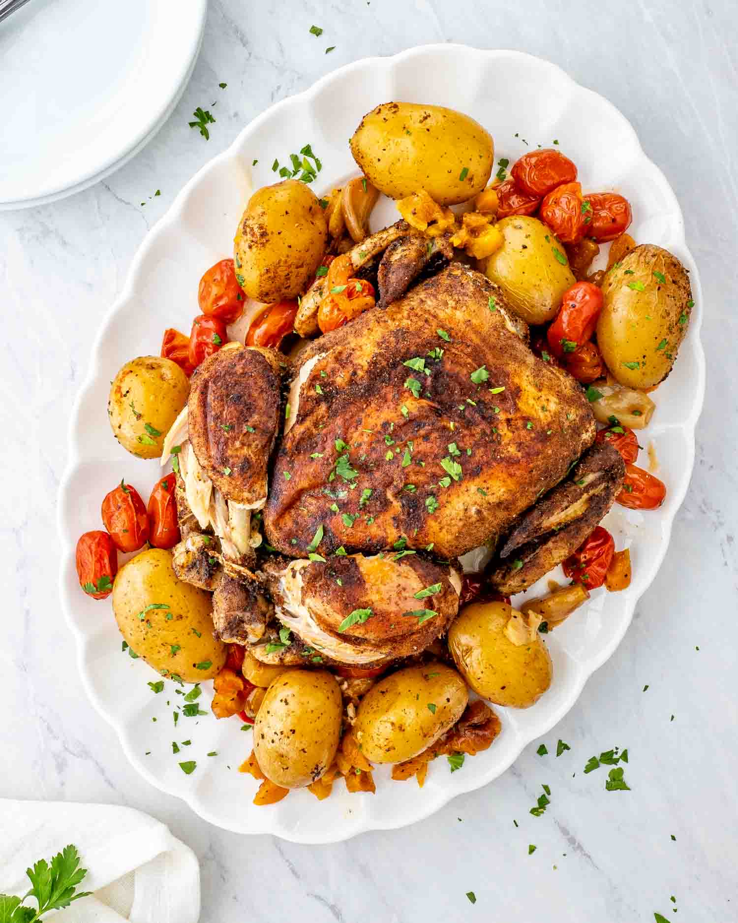 moroccan roast chicken and potatoes on a white serving platter.