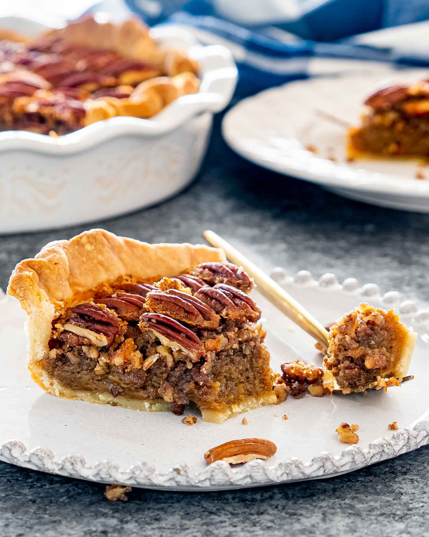 a slice of pecan pie on a white plate with a bite taken out of it.