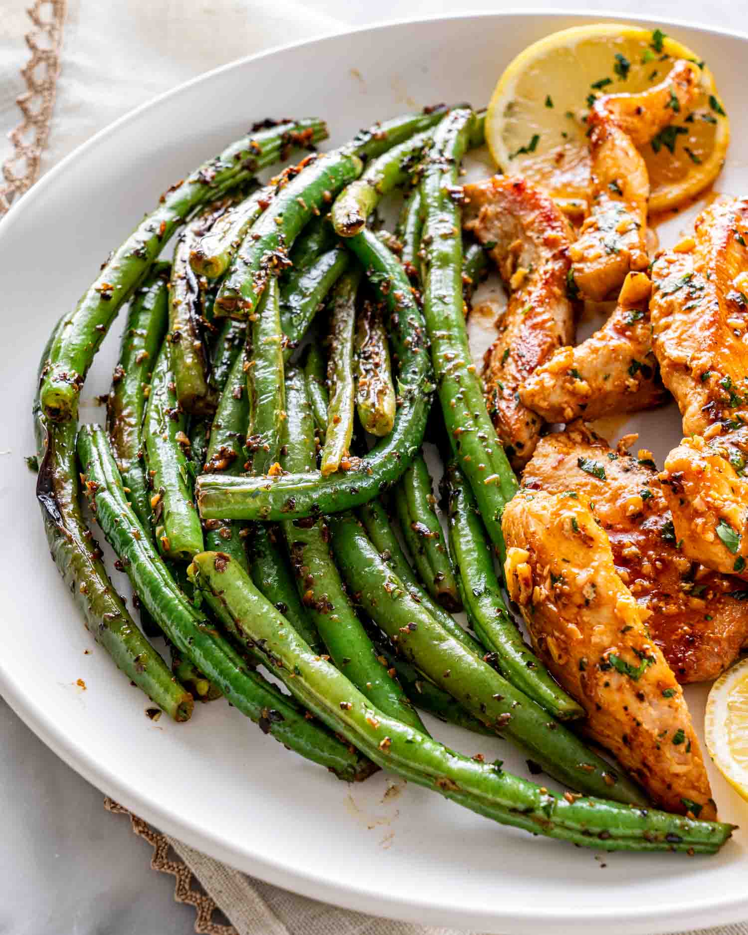 green beans with chicken on a white plate.