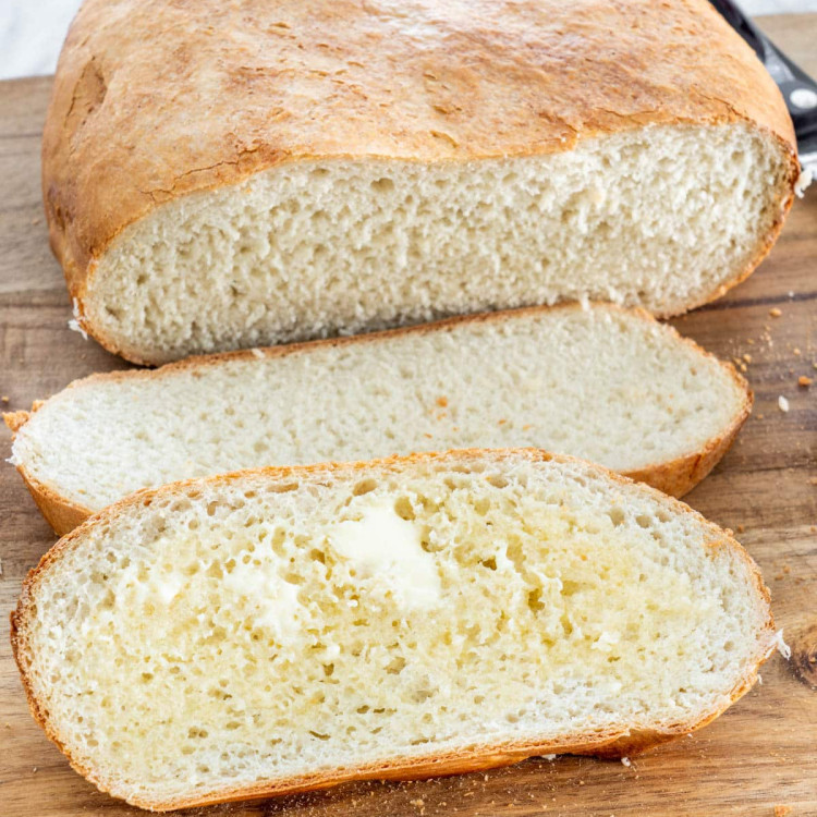 a loaf of slow cooker bread sliced in 2 pieces, one covered in butter