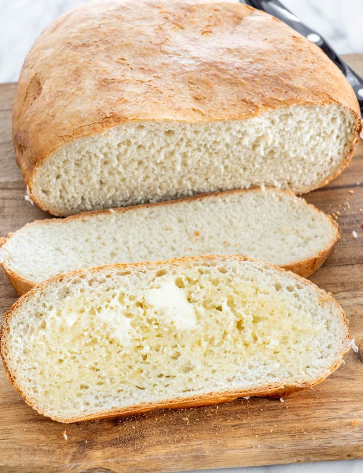 a loaf of slow cooker bread sliced in 2 pieces, one covered in butter