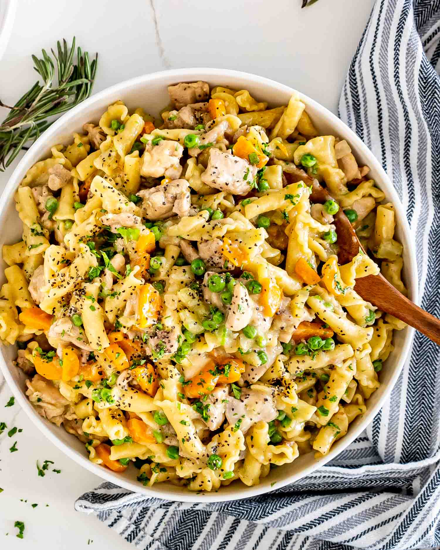 chicken pot pie pasta in a white serving bowl with a wooden serving spoon.