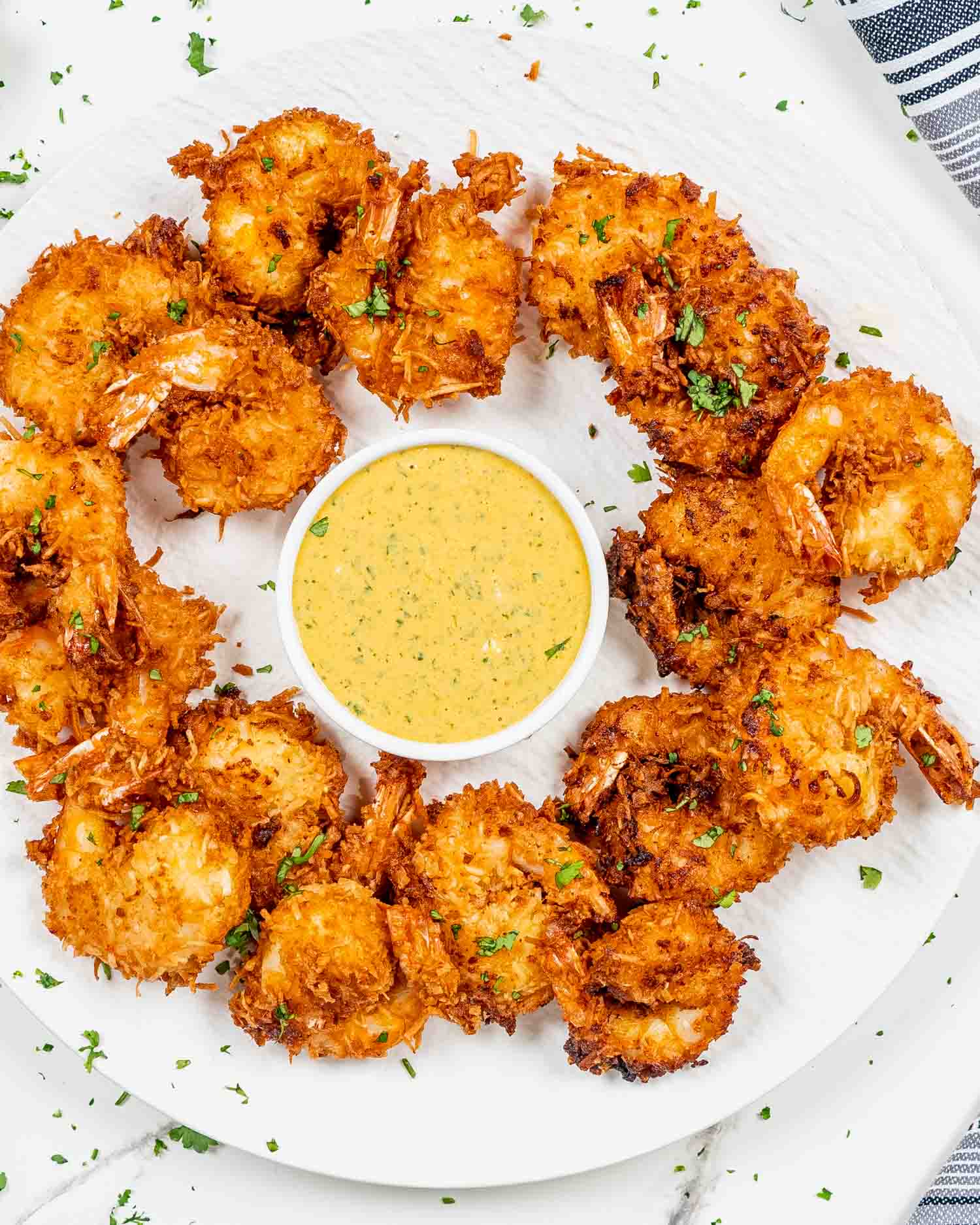 a plate full of coconut shrimp with spicy mango dipping sauce in a bowl.