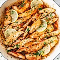 overhead shot of garlic butter chicken in a pan with lemon slices