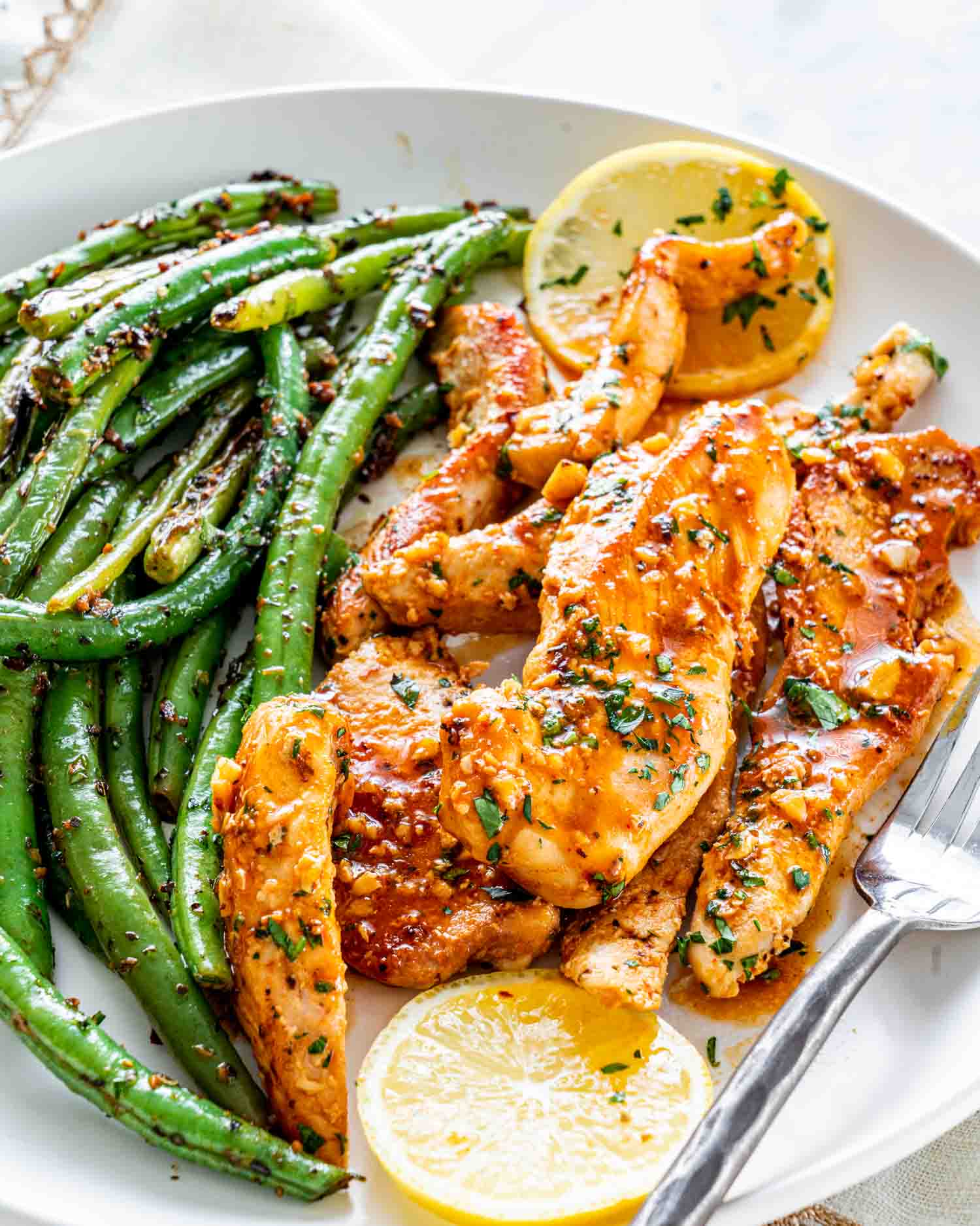 a serving of garlic butter chicken with green beans on a plate.