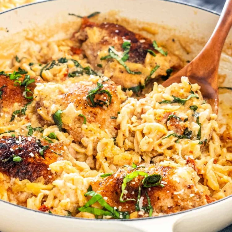 one pot chicken and orzo with a wooden spoon in it.