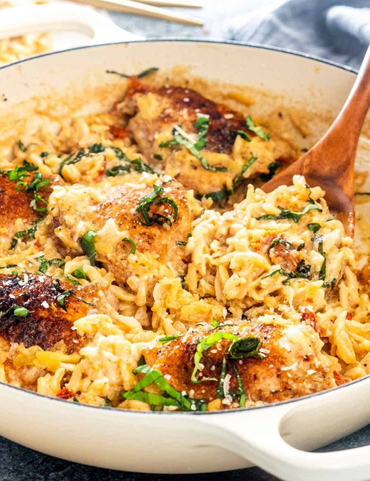 one pot chicken and orzo with a wooden spoon in it.
