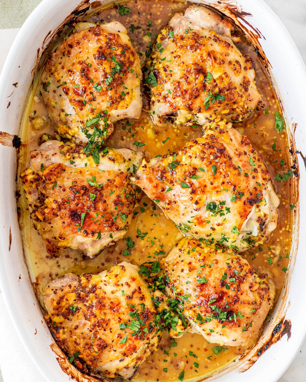overhead shot of oven baked chicken thighs in a white baking dish