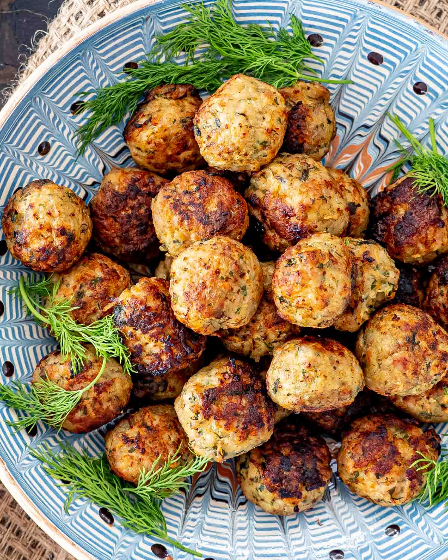 romanian meatballs in a clay bowl garnished with dill.