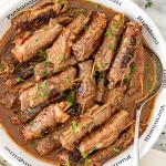 beef rouladen in a large serving bowl with a serving spoon.
