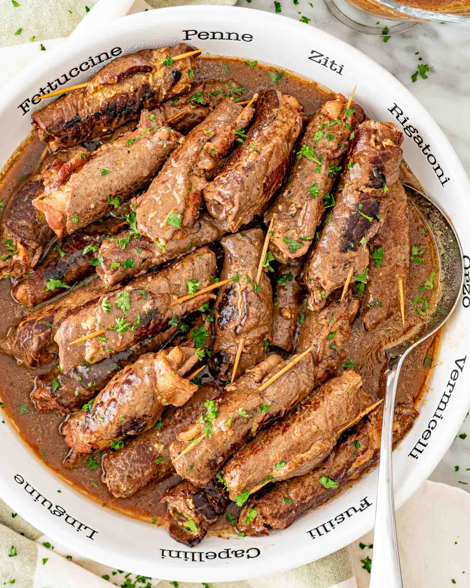 beef rouladen in a large serving bowl with a serving spoon.