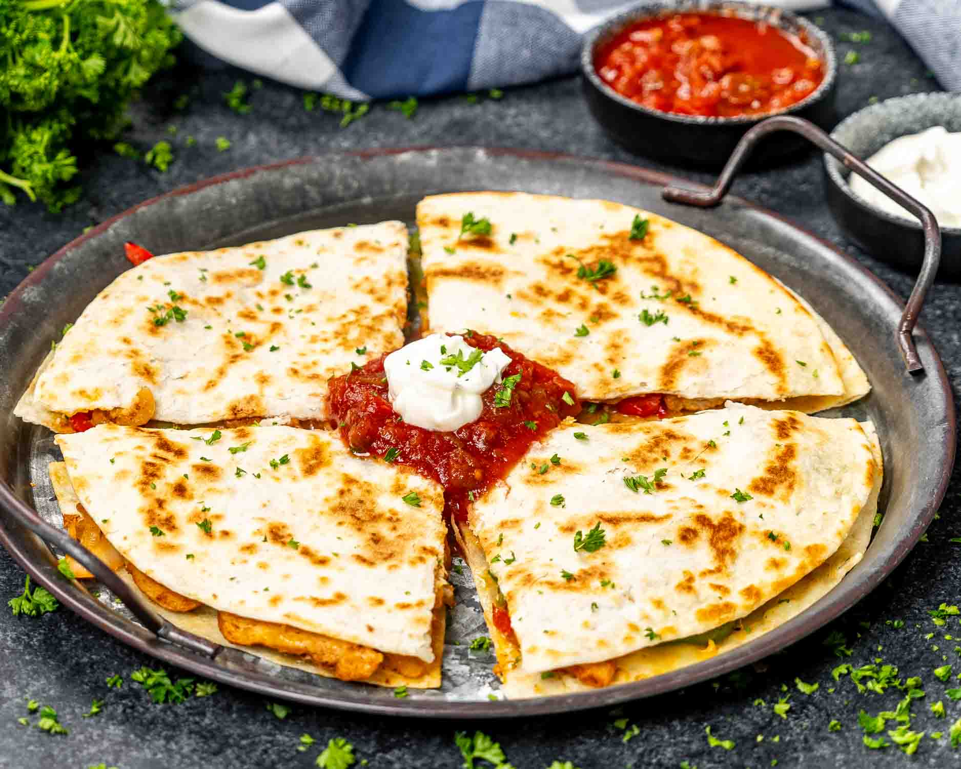 a stack of chicken fajita quesadillas with some salsa on a plate and garnished with parsley.