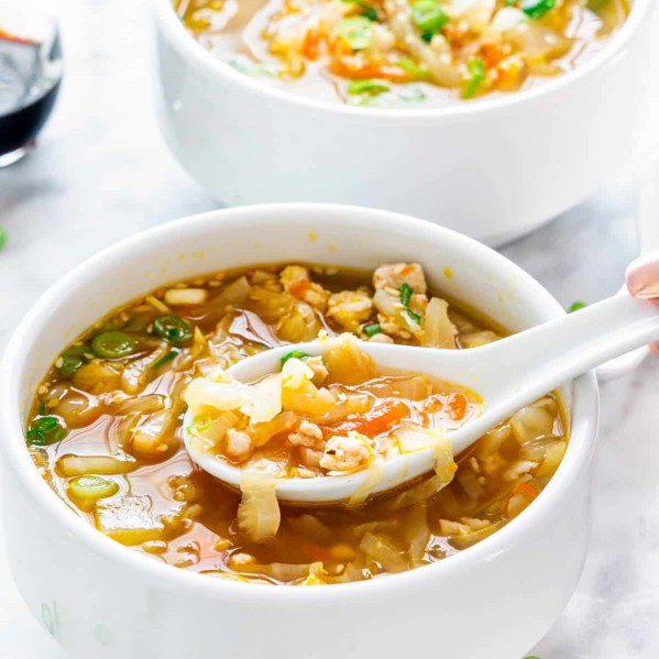 a soup spoon taking a bite of egg roll soup from a bowl