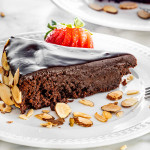 a slice of flourless chocolate cake on a plate garnished with a sliced strawberry