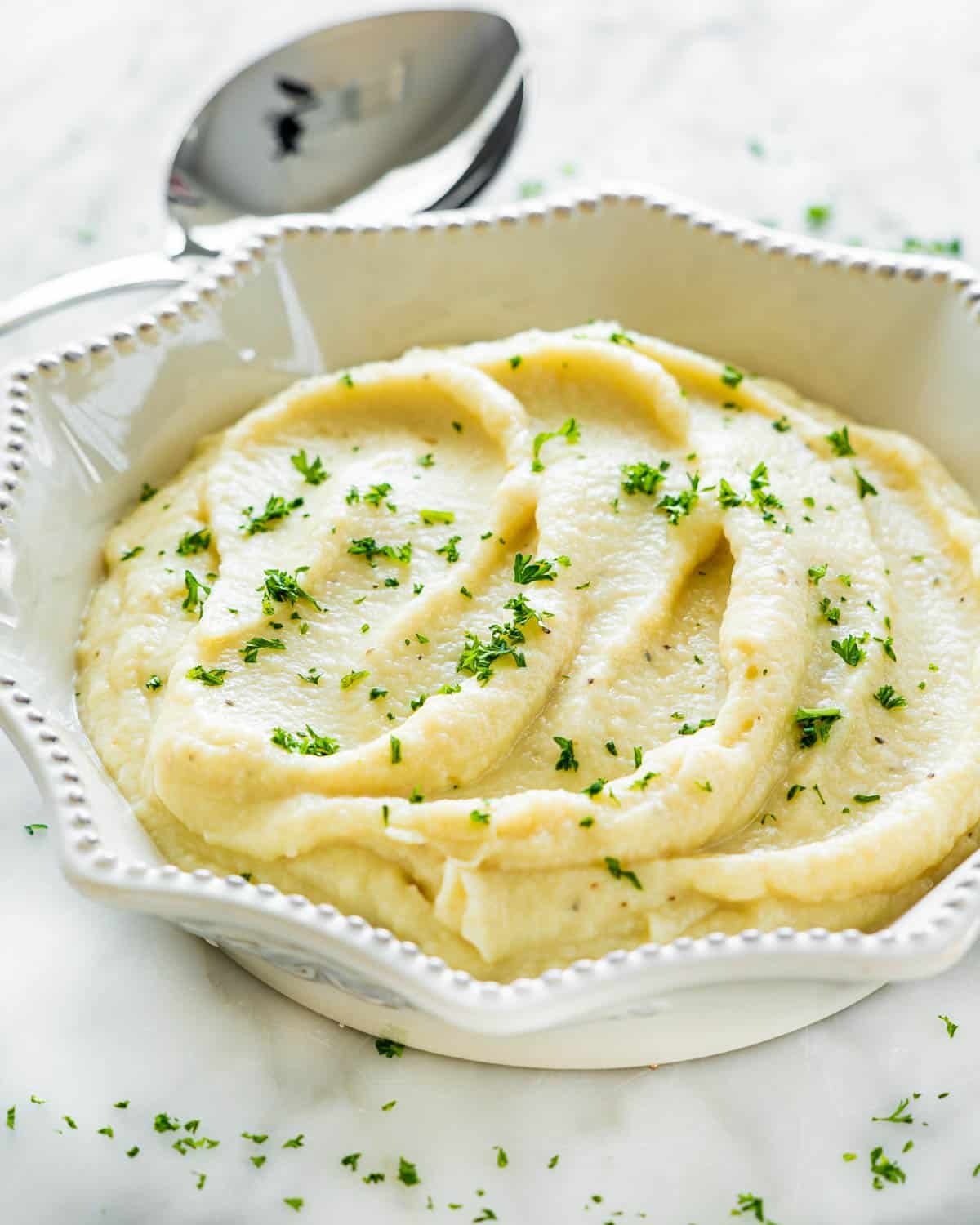instant pot mashed cauliflower in a white bowl garnished with parsley
