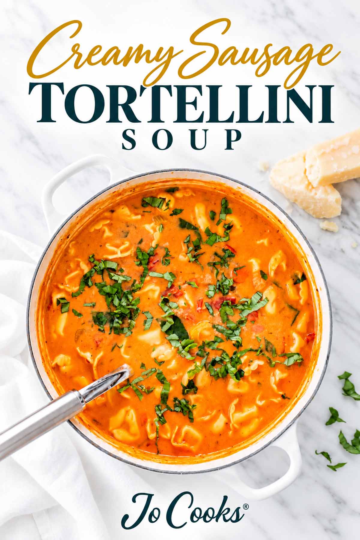 Overhead pot of creamy sausage tortellini soup garnished with basil beneath gold and teal recipe lettering and Jo Cooks logo.