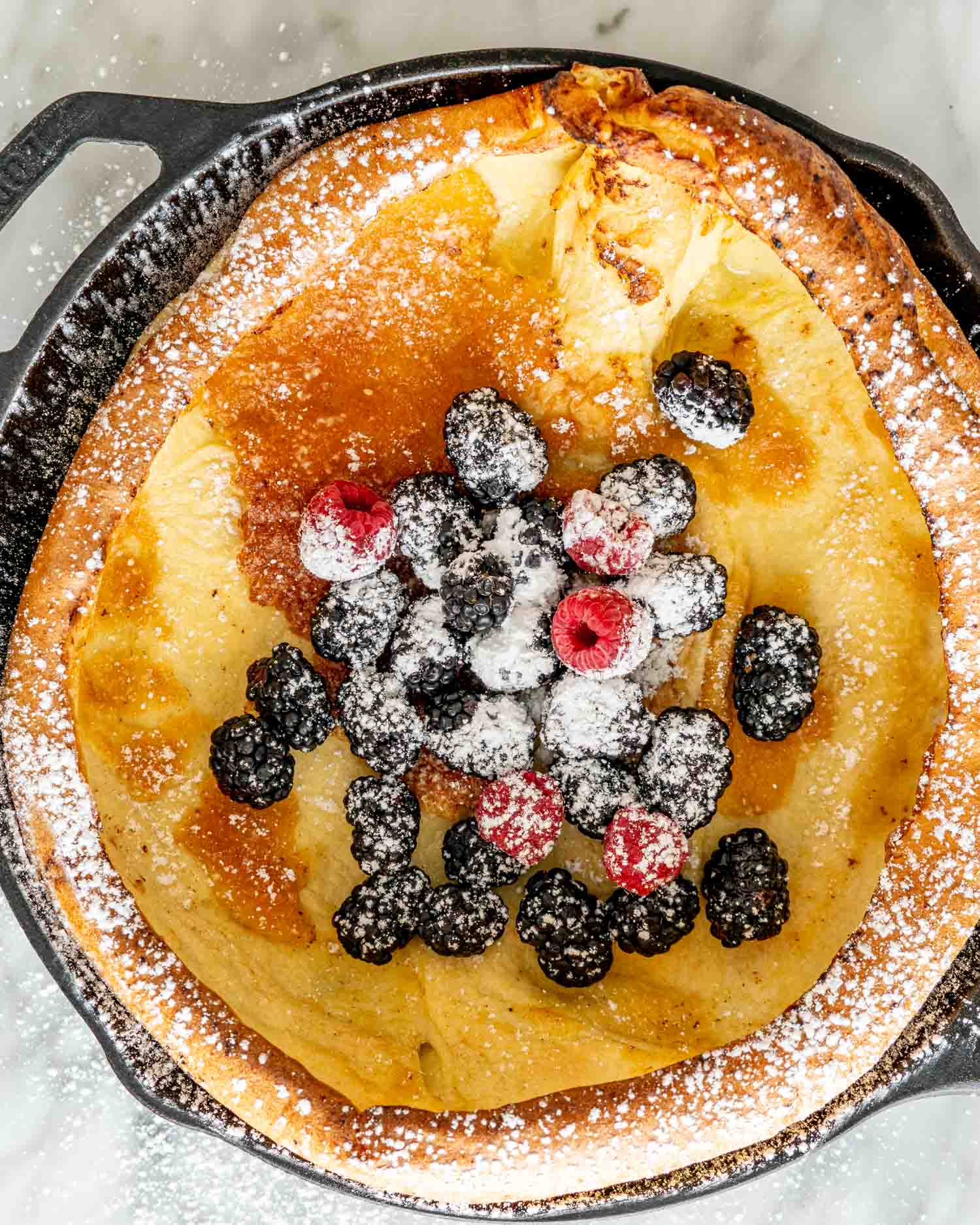 dutch baby pancake in a cast iron skillet topped with berries.