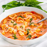 side view shot of tortellini soup in a bowl with a spoon in it