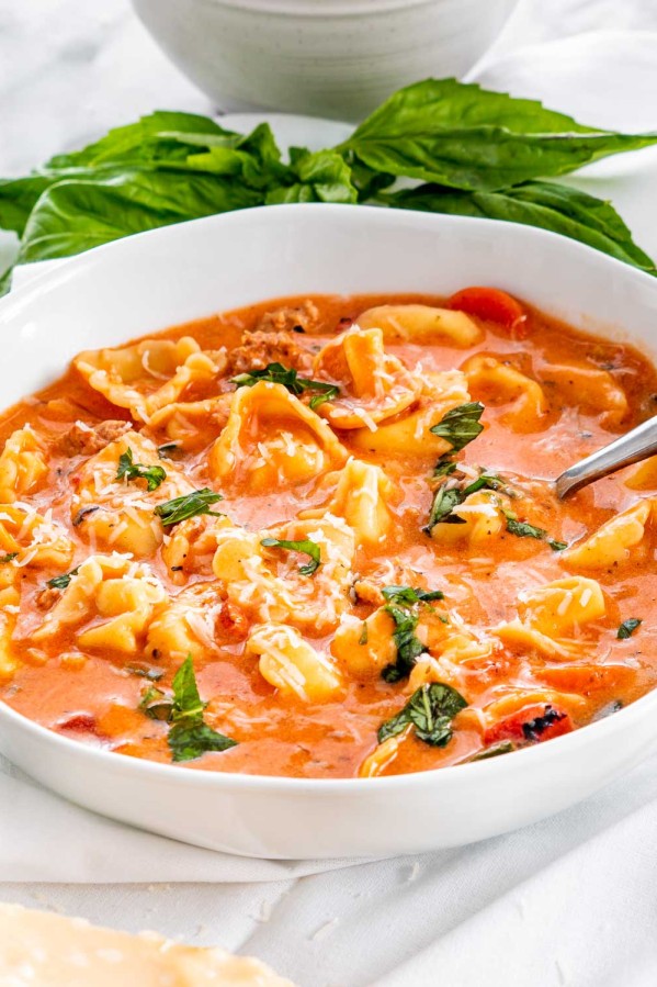side view shot of tortellini soup in a bowl with a spoon in it