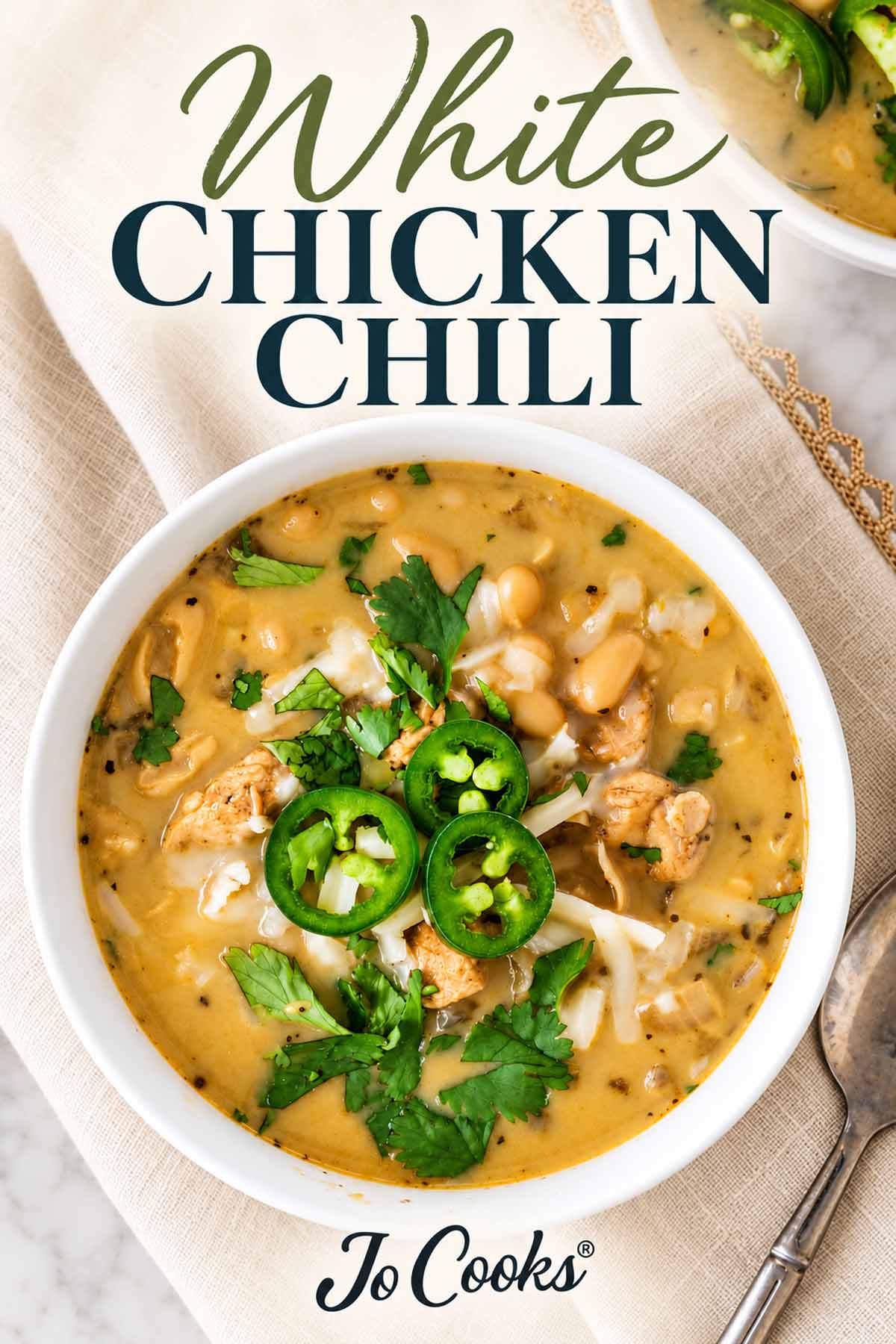 White chicken chili topped with jalapeños, cheese, and cilantro, with recipe title above and Jo Cooks logo below.