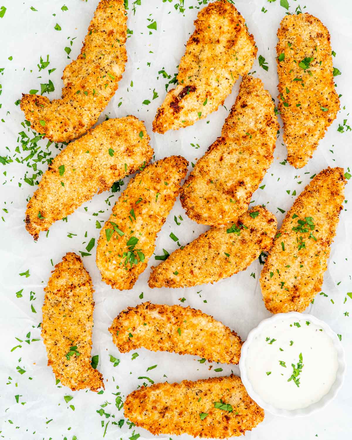 overhead shot of air fryer chicken tenders with ranch dressing garnished with parsley