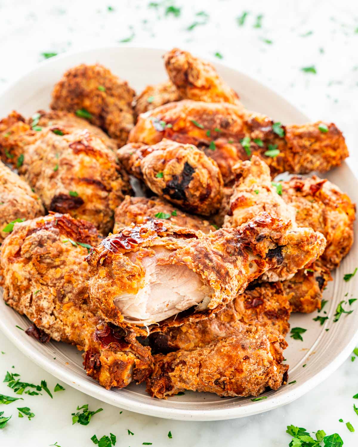 fried chicken on a serving platter with a chicken drumsticks sitting on top with a bite taken out of it