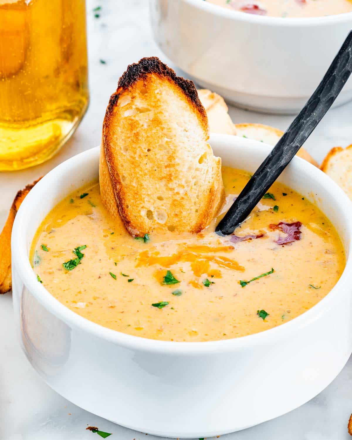 bacon beer cheese soup in a white bowl with a slice of toast in it