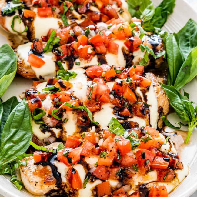 side view shot of bruschetta chicken lined up on a plate