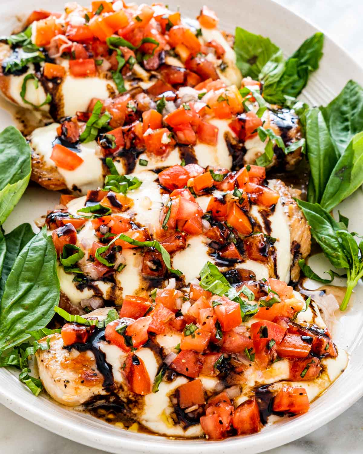 4 pieces of bruschetta pieces garnished with basil leaves on a serving platter