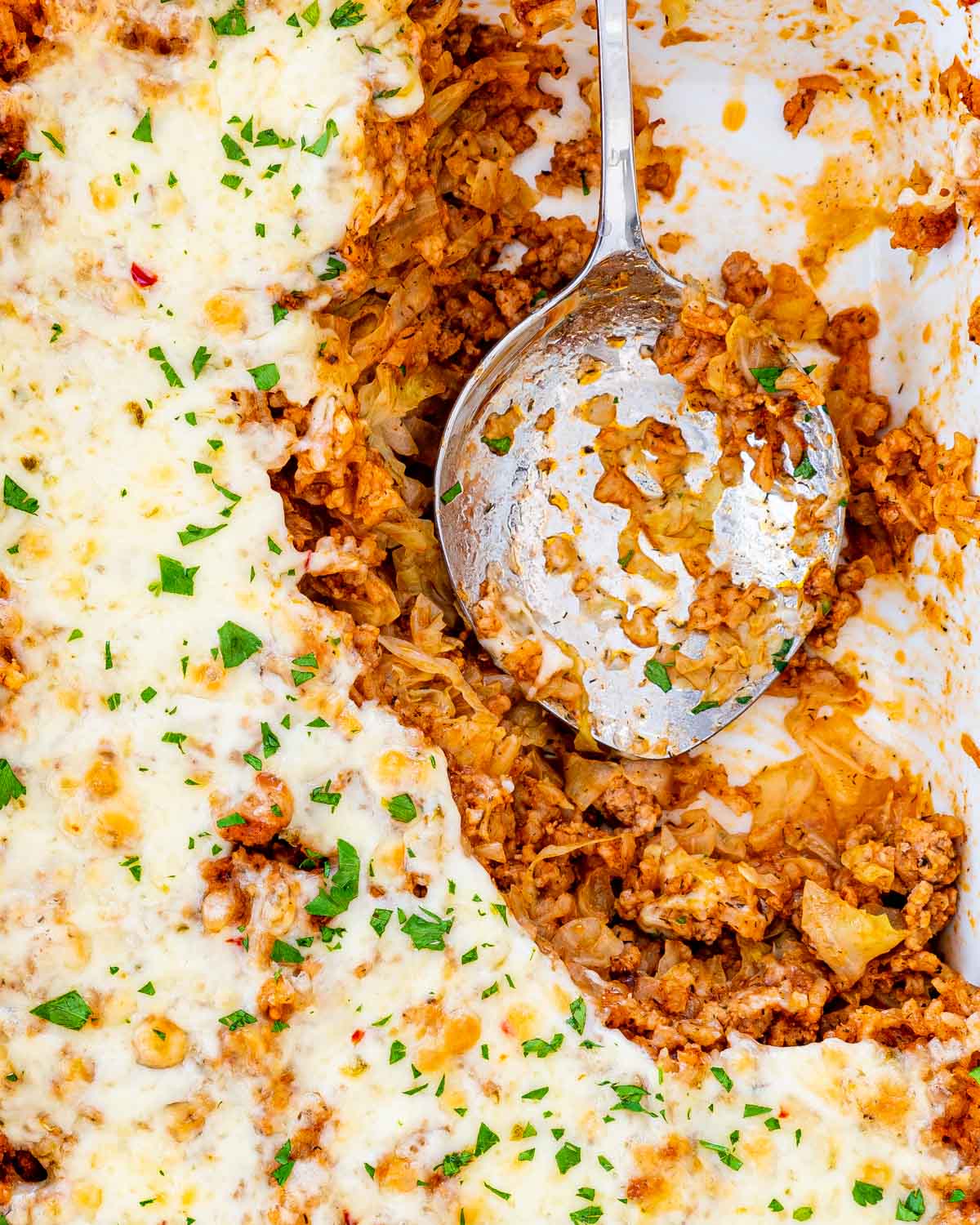 Overhead shot of cabbage roll casserole in a casserole dish with a serving spoon inside