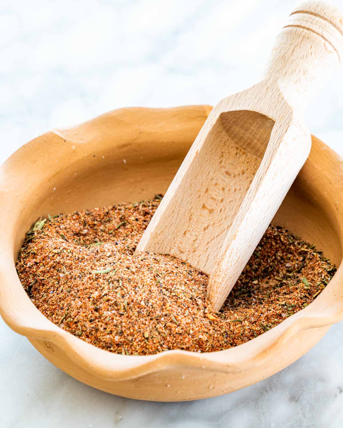 homemade cajun seasoning in a bowl with a wooden scoop inside