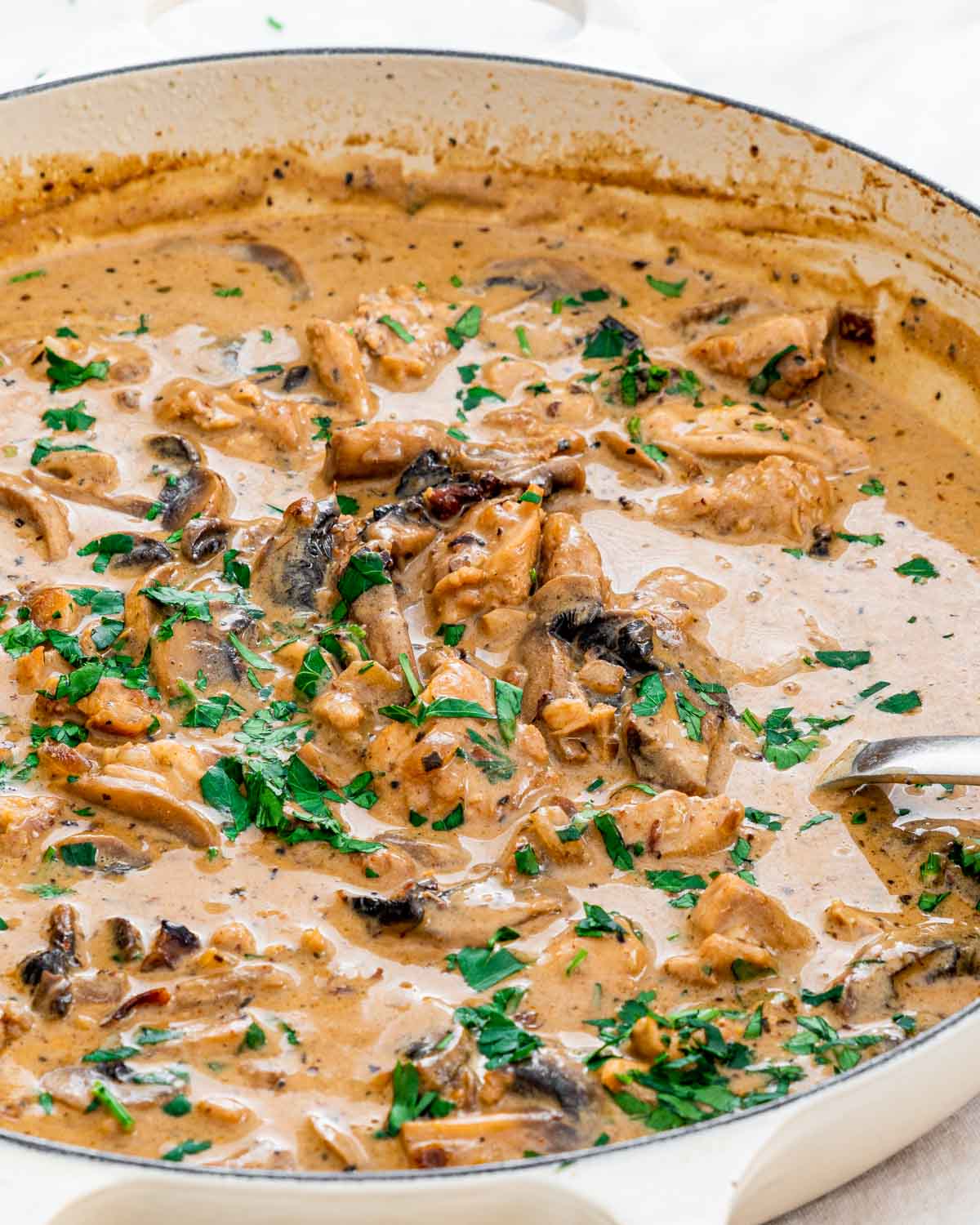 chicken and mushroom stew in a large braiser garnished with parsley